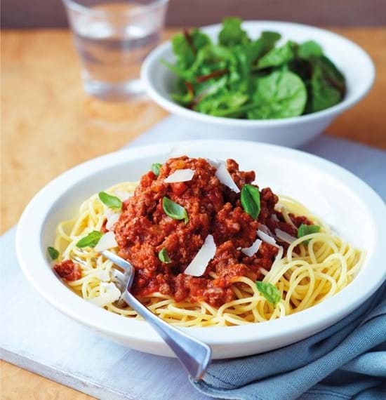 Spaghetti Bolognese dish set out on a table with salad